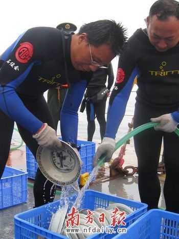 考古人员对打捞上来的瓷器进行冲洗去除附着物。